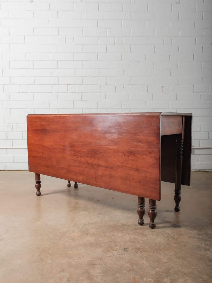 Antique Drop-Leaf Dining Table: Classic wooden drop-leaf table featuring turned legs and a warm, time-softened finish. The hinged leaves allow for flexible sizing, making it ideal for smaller dining spaces or as a multifunctional wo