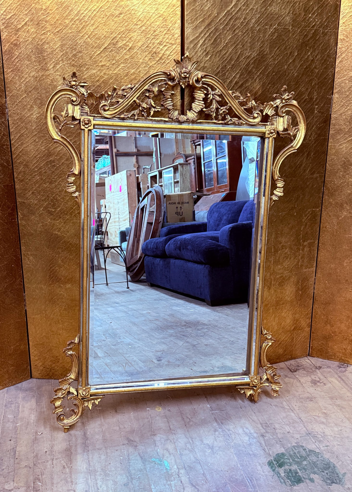 Italian Giltwood Beveled Wall Mirror: Italian giltwood wall mirror featuring an ornate Rococo-style frame with elaborate scrollwork, floral carving, and decorative crest. The rectangular mirror plate is beveled and set within a richly det