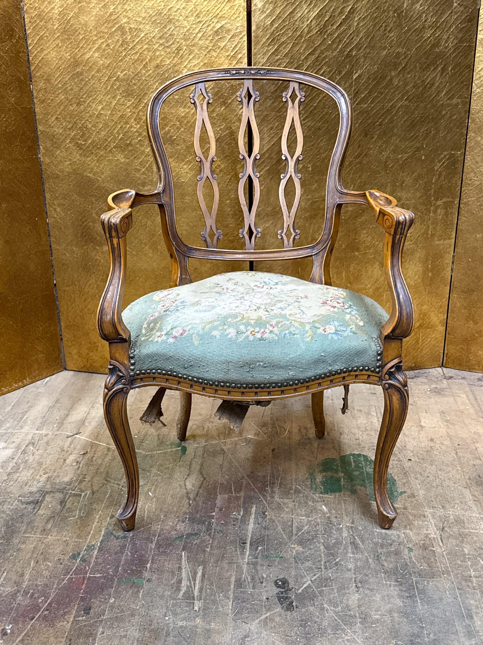 Needlepoint Armchair with Brass Details: Needlepoint upholstered arm chair featuring a carved wood frame with decorative open back splats and curved arms. The seat is upholstered in needlepoint fabric with brass nail head trim, along with br