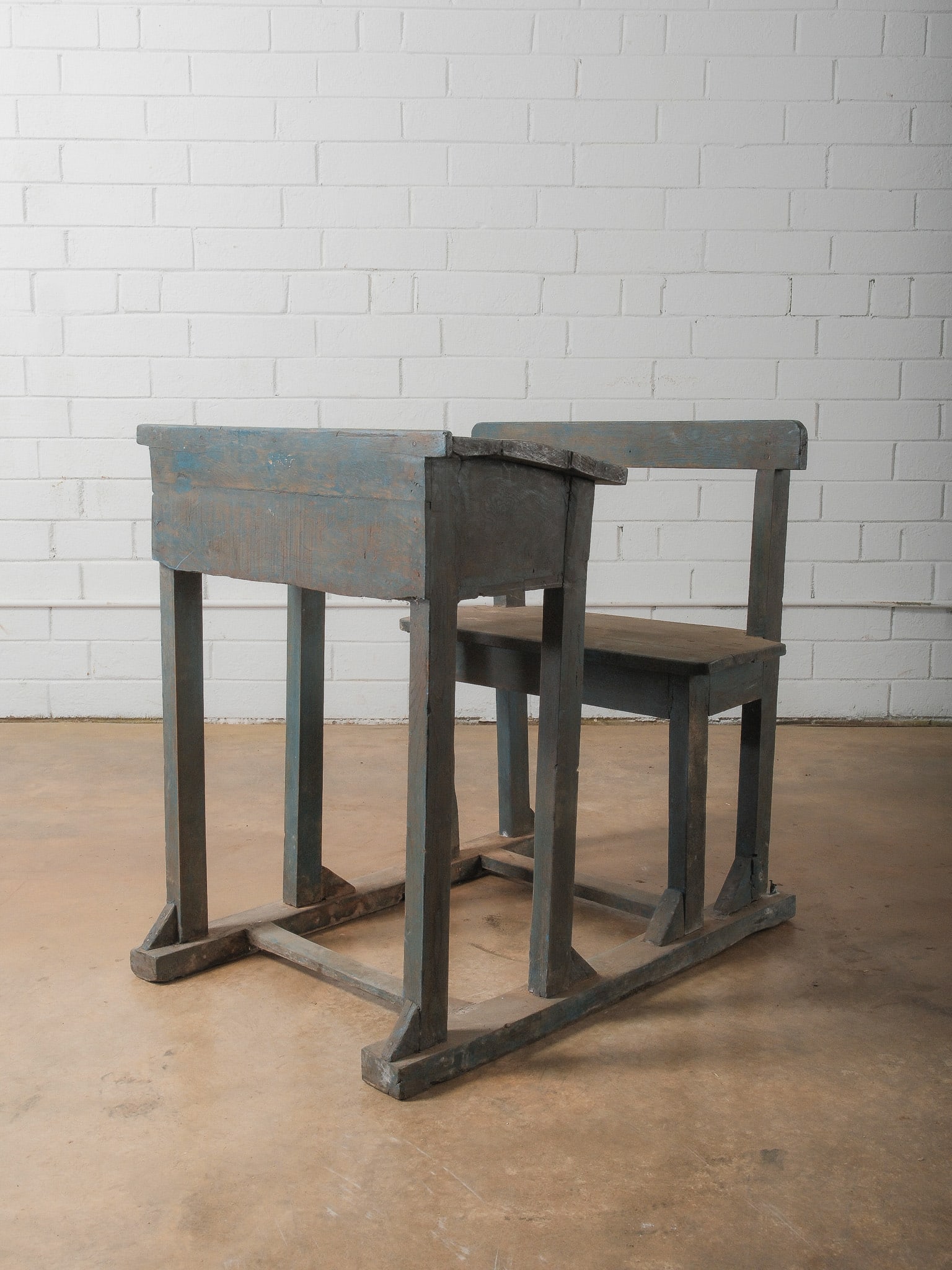 Primitive Wooden School Desk: Rustic wooden school desk featuring attached bench seating and lift-top writing surface. Finished in a distressed blue-gray paint with visible wear and age. Strong primitive character ideal for