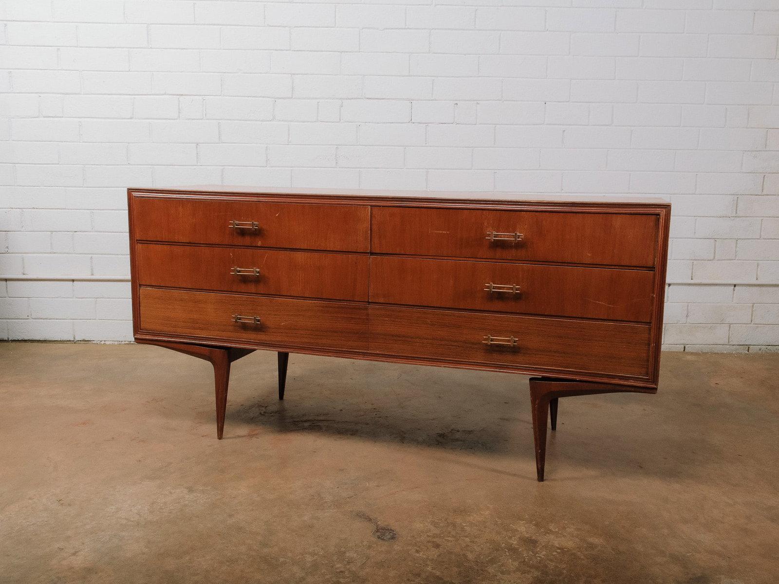MCM Dresser: Mid-century modern dresser featuring six spacious drawers, sculpted tapered legs, and original brass hardware. Clean architectural lines and rich walnut grain make this a timeless storage piece for a