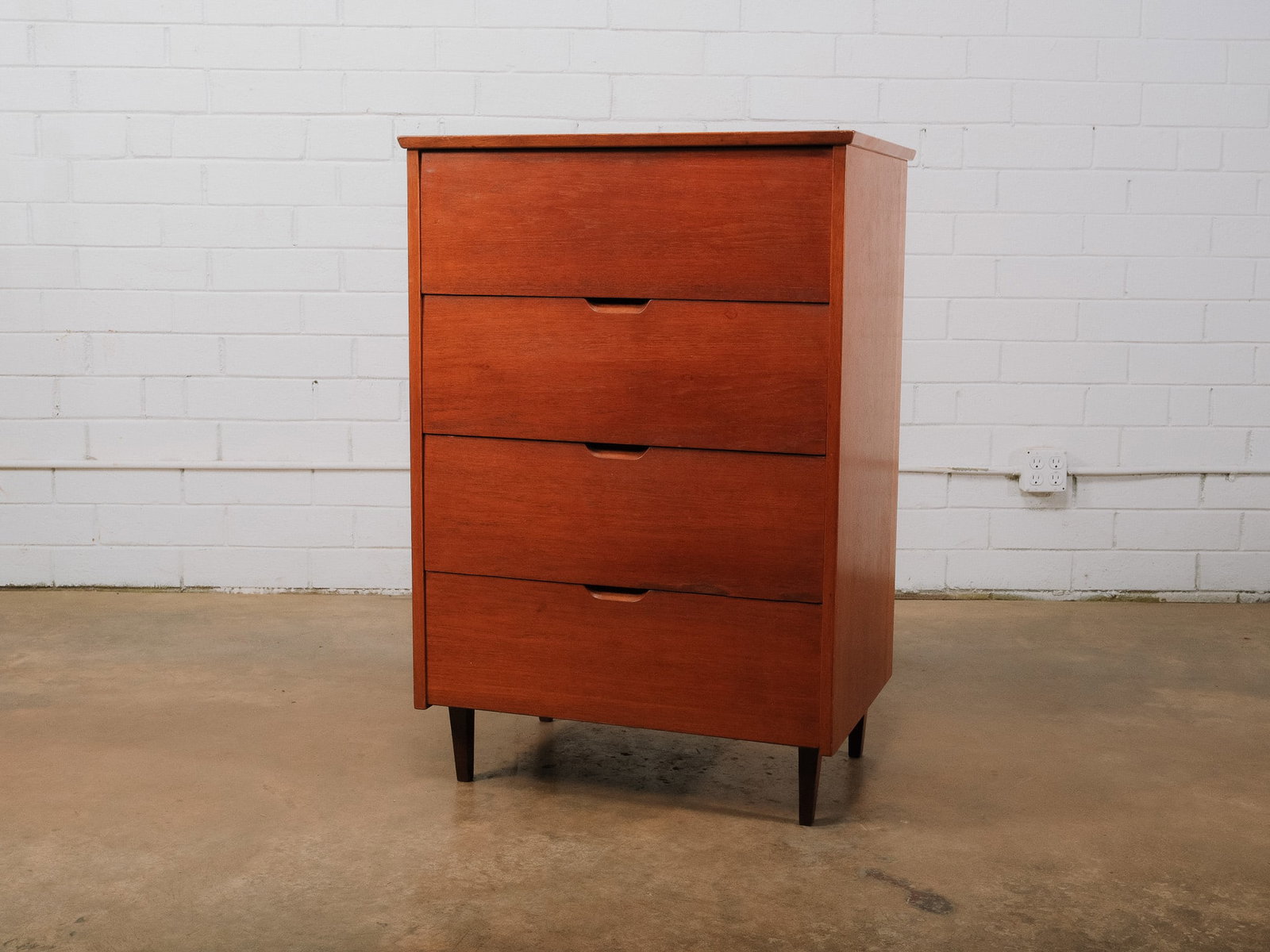 Mid-Century Modern Four-Drawer Chest: Mid-century modern four-drawer chest featuring a clean-lined case with integrated recessed finger pulls and tapered legs. The minimalist design and warm wood finish exemplify classic MCM styling,