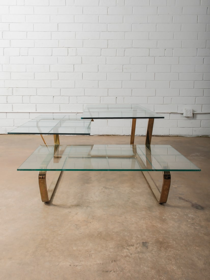 Modern Glass & Brass Coffee Table: Low-profile coffee table with layered glass surfaces supported by a minimalist metal frame in a warm brass tone. Clean lines and transparency give this piece a light, modern feel while offering ample