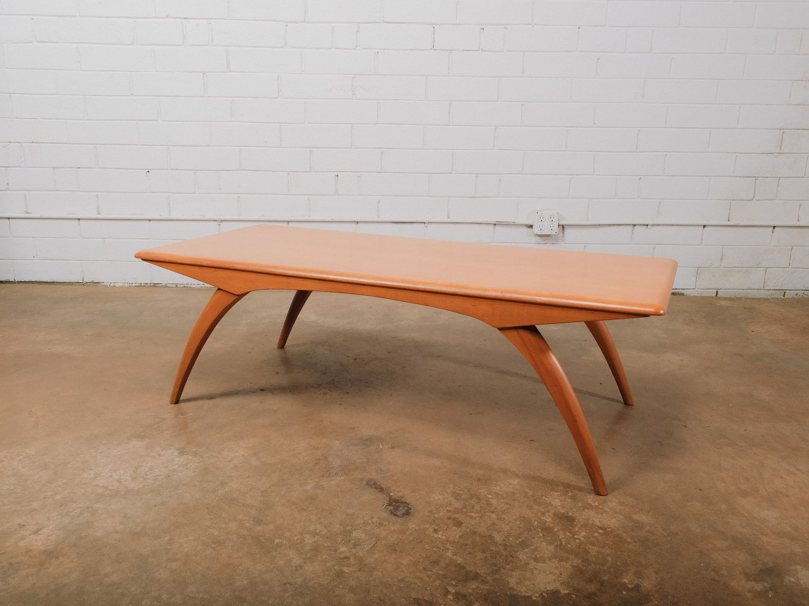Mid-Century Coffee Table: Mid-century modern coffee table with a softly rounded rectangular top and distinctive arched, tapered legs. The clean, sculptural silhouette and warm wood finish make it a versatile centerpiece for a 