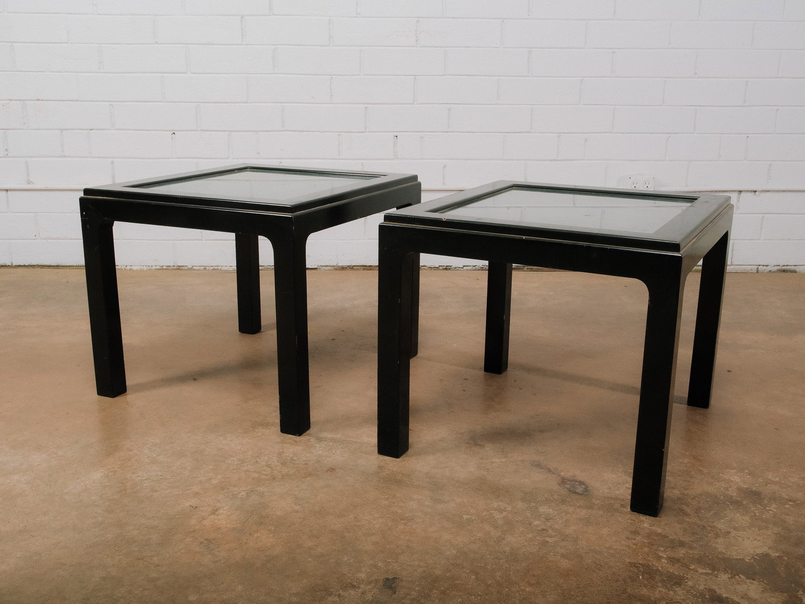 Pair of Black Wood Glass Top Accent Tables: Pair of black wood accent tables featuring inset glass tops that showcase decorative carved panels beneath the glass. The concealed artwork adds a unique, Asian-inspired decorative element while the c