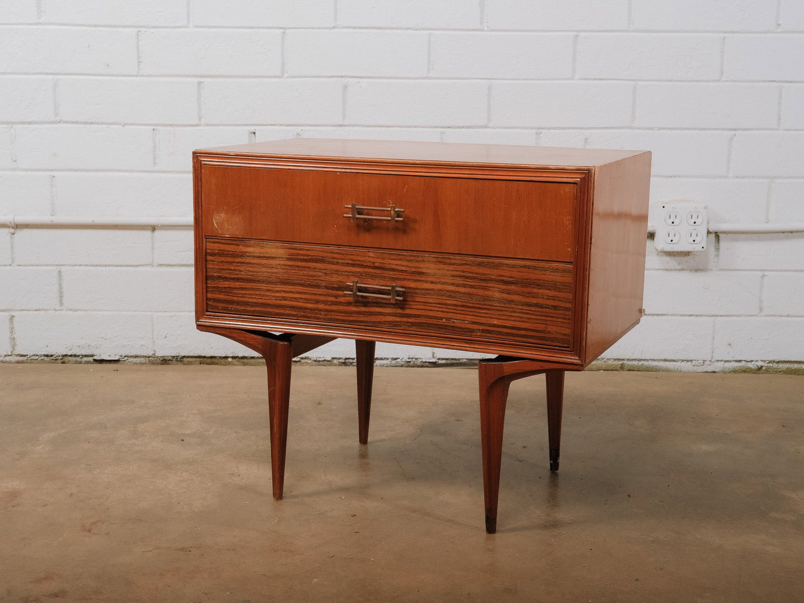 MCM Single Nightstand: Mid-century modern nightstand featuring two spacious drawers, sculpted tapered legs, and original brass hardware. A warm walnut finish and clean lines make this a versatile bedside or accent cabinet. 