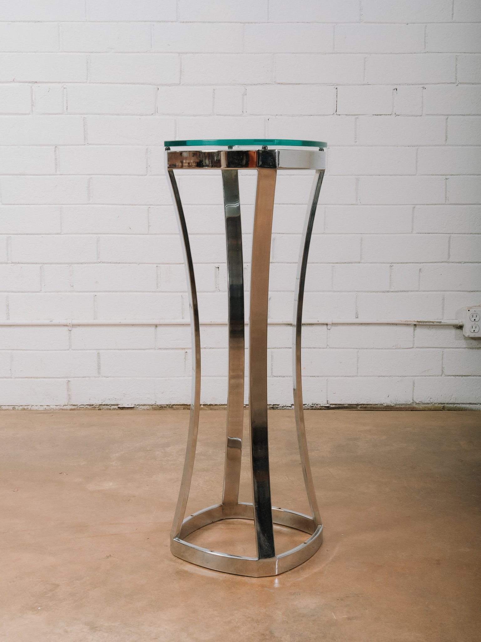 Modern Chrome and Glass Pedestal Accent Table: Modern pedestal accent table featuring a thick round glass top supported by a sculptural polished chrome base with gracefully curved legs and a circular stretcher. The sleek combination of glass and c