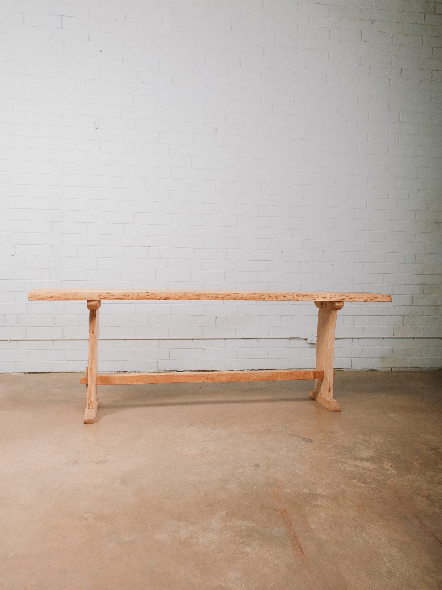 Live Edge Console Table with Trestle Base: Rustic contemporary live edge console table featuring a thick solid wood slab top with natural live edges, supported by a substantial trestle base with sturdy stretcher. The clean architectural form
