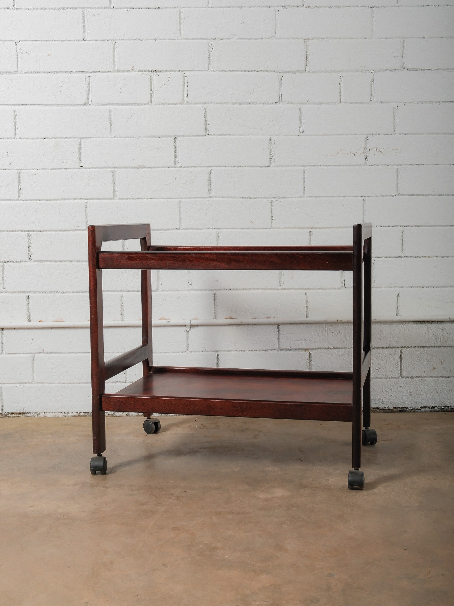 Mid-Century Modern Rolling Cart: This mid-century modern bar cart features a two-tier open design with clean, rectilinear lines and a warm wood finish. Supported on four casters for easy mobility, the cart offers ample surface space