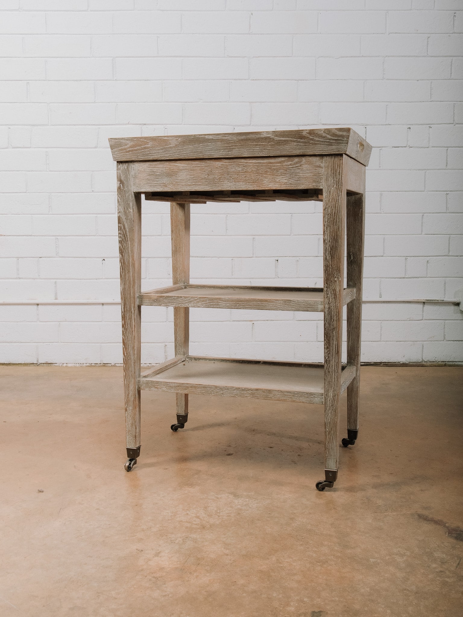 Rolling Wood Cart with Lift-Top Tray: Rolling wood utility cart featuring a removable lift-top tray, integrated bottle storage, and two lower shelves for additional storage or display. Mounted on casters for easy mobility, making it