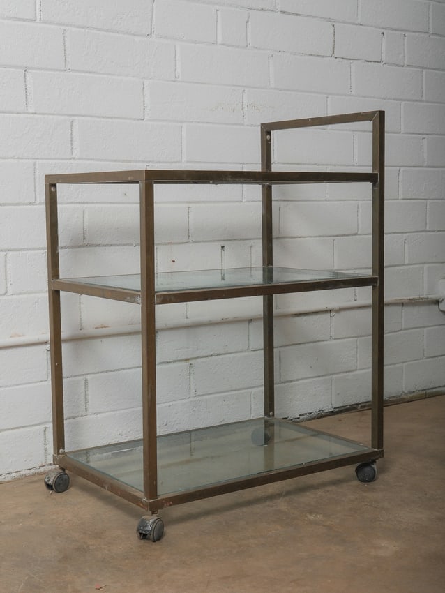 Mid-Century Modern Brass & Glass Bar Cart: A minimalist mid-century modern rectangular bar cart featuring two inset glass shelves framed within a square brass-plated metal structure. The open-form design allows for easy access from all sides,