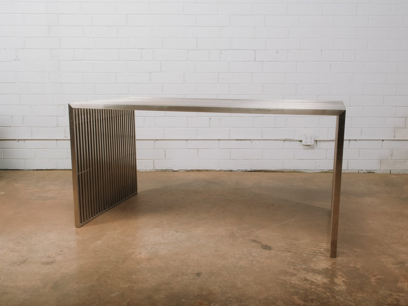 Contemporary Slatted Metal Dining Table: Contemporary dining table featuring a brushed metal frame with waterfall-style sides. The clean linear design and generous rectangular top make it an eye-catching centerpiece for modern, industrial,