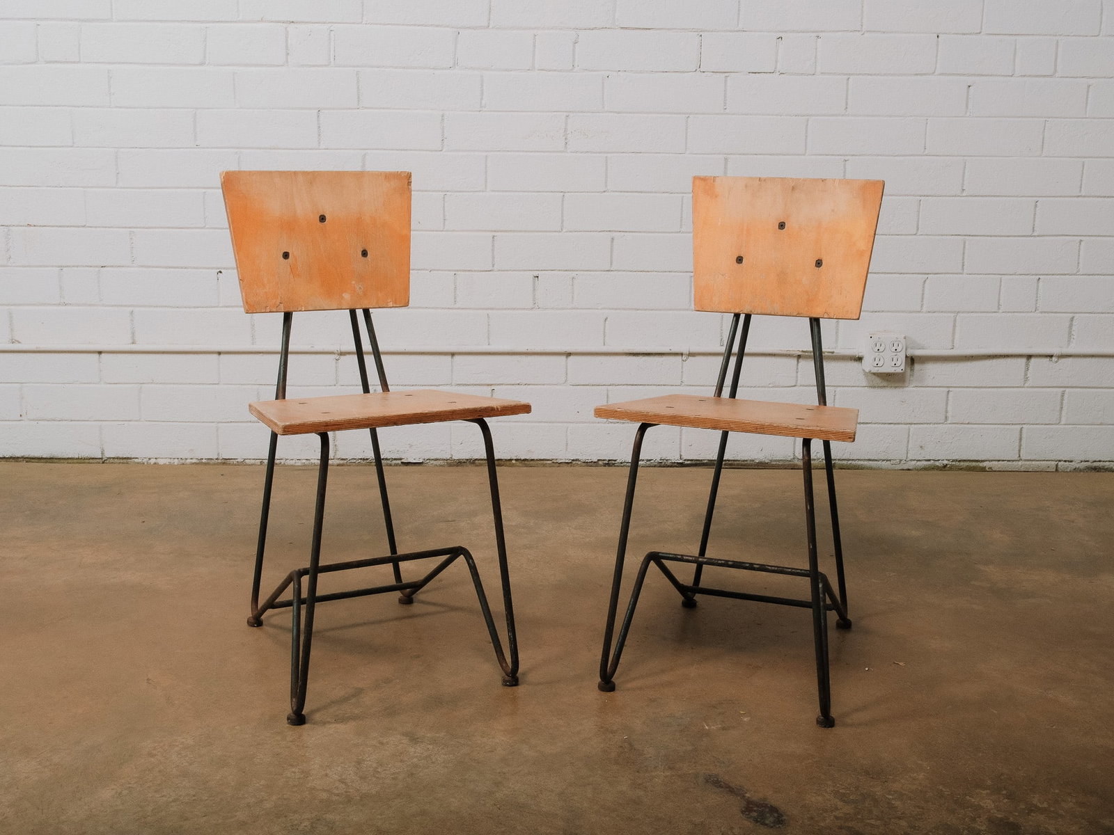 Pair of Industrial Wood & Metal Side Chairs: Pair of industrial-style side chairs featuring bent metal rod frames with solid wood seats and backrests. The minimalist design blends warm natural wood with black metal for a versatile look that
