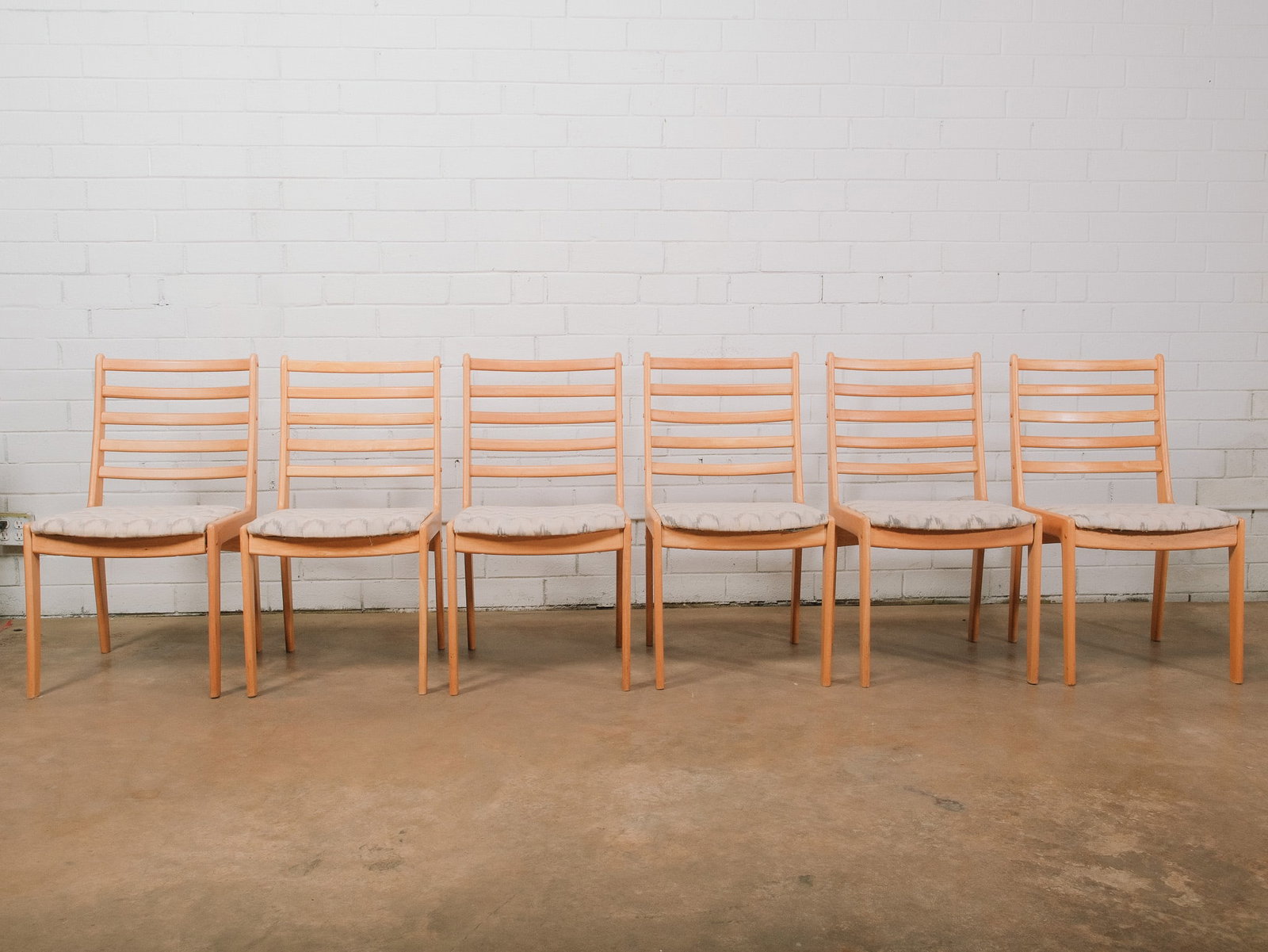 Set of 6 Armless Modern Wood Dining Chairs: Set of six modern dining chairs featuring light wood frames with gently curved ladder backs and upholstered fabric seat cushions in a neutral patterned fabric. Their clean Scandinavian-inspired