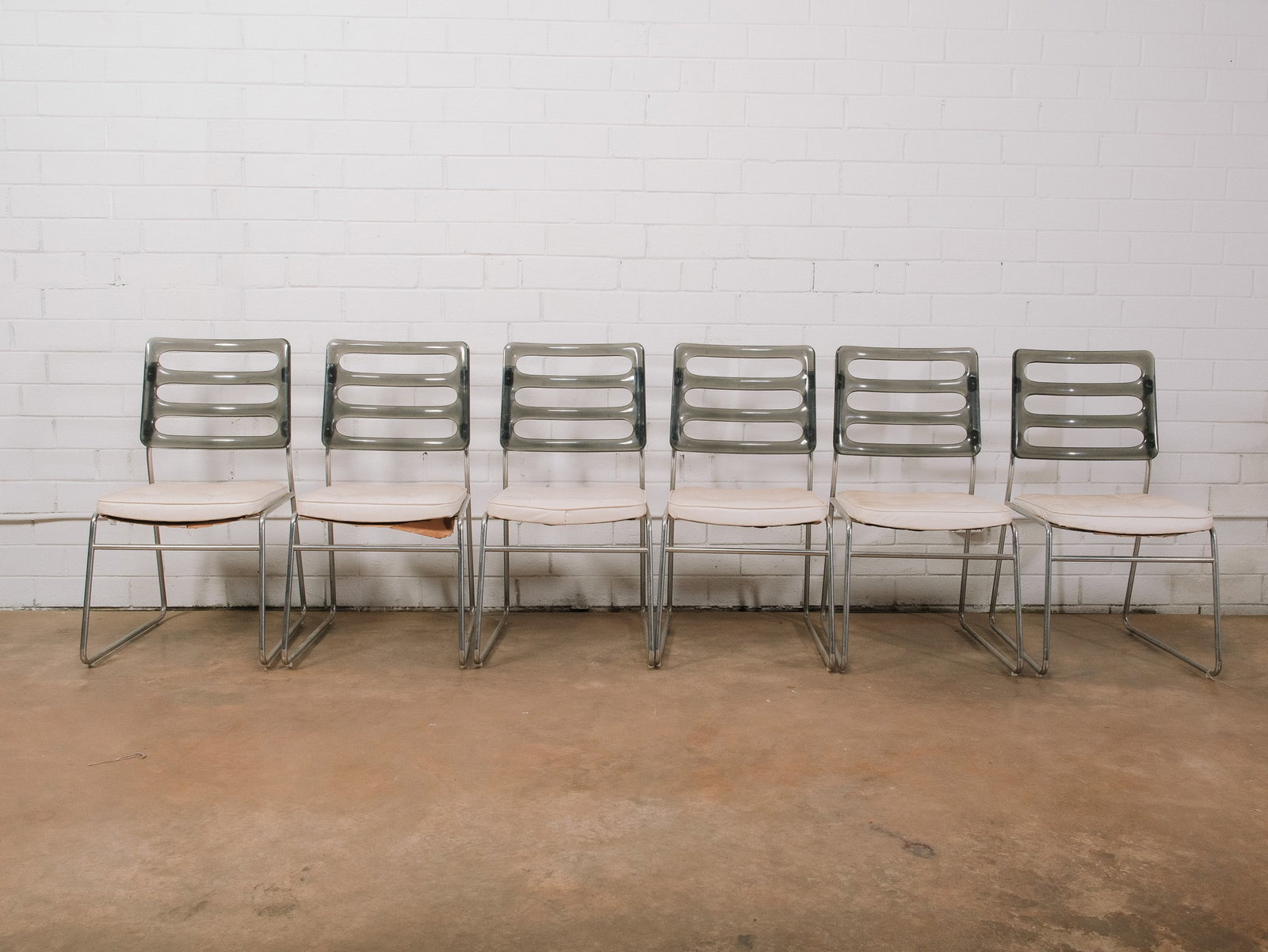Set of 6 Modern Dining Chairs: Set of six modern armless dining chairs featuring smoked gray molded ladder-back seats, chrome sled bases, and white upholstered seat cushions. Their clean-lined design blends molded plastic, tubular 