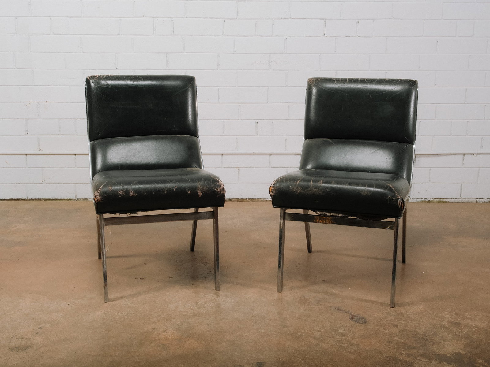 Pair of MCM Chrome Accent Chairs: Pair of mid-century modern side chairs featuring sleek chrome frames and black vegan leather upholstery. The clean-lined silhouettes make them ideal as accent chairs, while the polished chrome bases