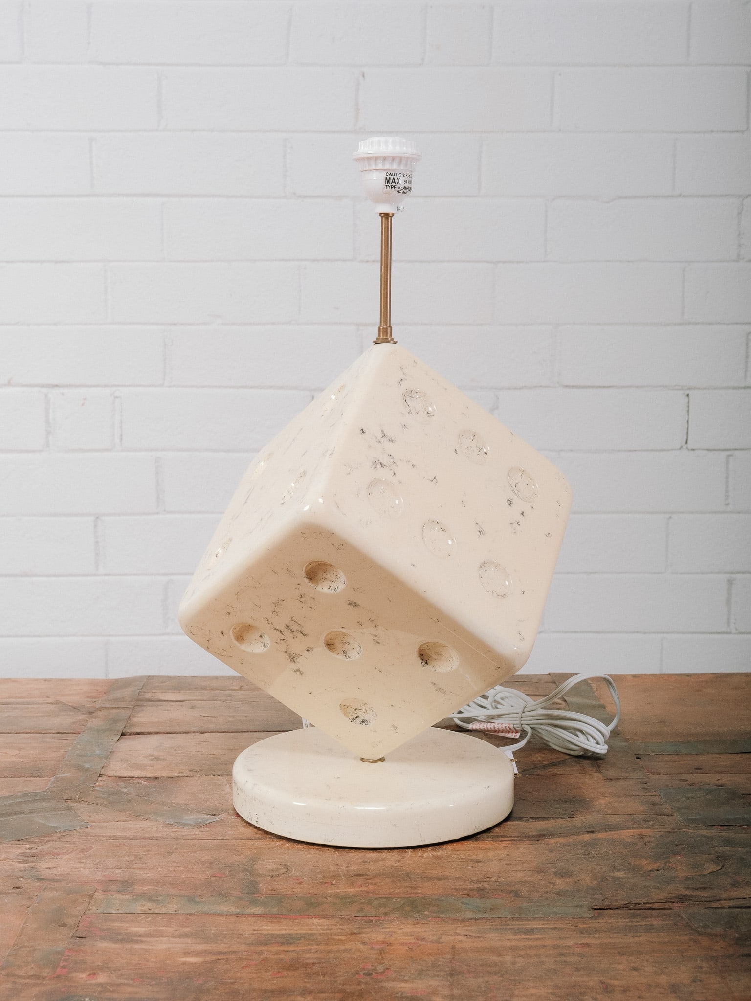 Brutalist Style Cube Table Lamp: Brutalist-style table lamp featuring a carved cube-form resin shade with pierced geometric openings mounted on a round white base. The sculptural design creates dramatic light patterns when illuminate
