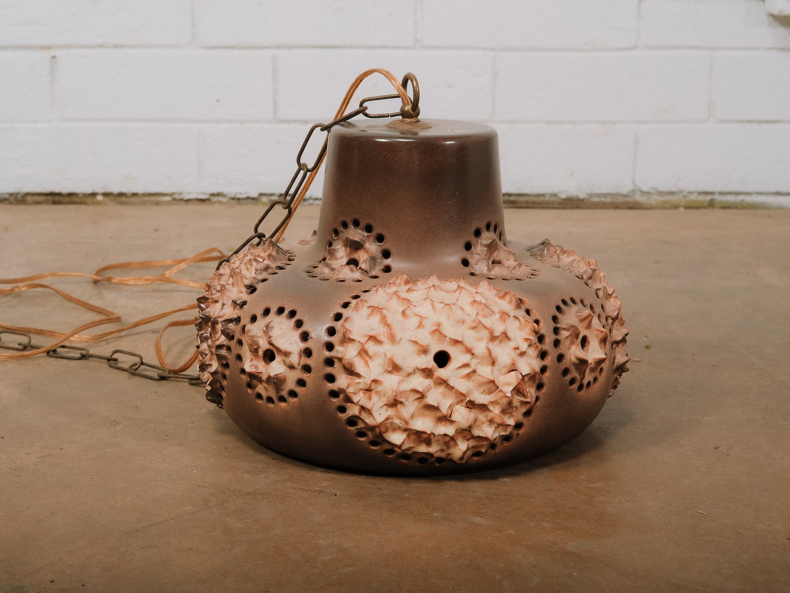 Brown and Cream Pottery MCM Pendant Light: Vintage Brutalist-style ceramic pendant light featuring an earthy brown glaze with sculptural raised floral motifs and hand-pierced perforations that create a warm ambient glow when illuminated. A