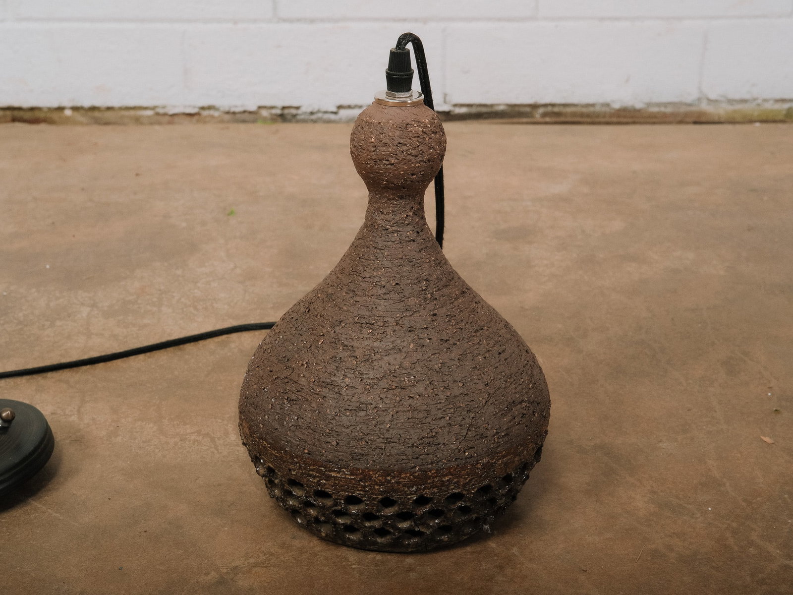 Brown Pottery MCM Pendant Light: Vintage studio pottery pendant light with a cylindrical hand-thrown ceramic shade featuring textured clay surfaces and dramatic red glazed organic openings. The sculptural form emits warm accent