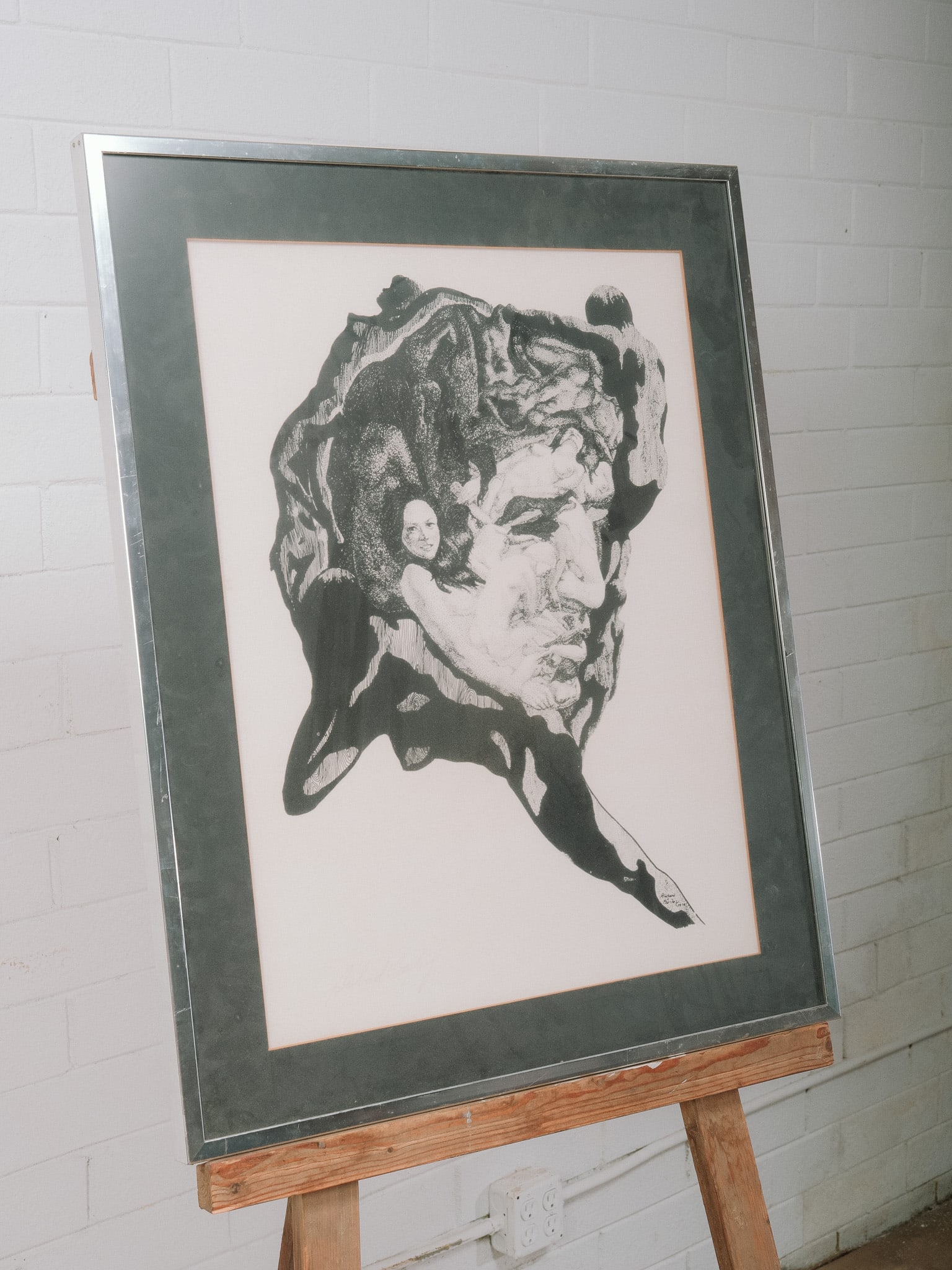 Framed Black & White Surrealist Figure Print: Black and white surrealist print depicting intertwined figures within an abstract organic composition. Matted and presented under glass in a brushed silver-tone frame. Pencil signed and numbered