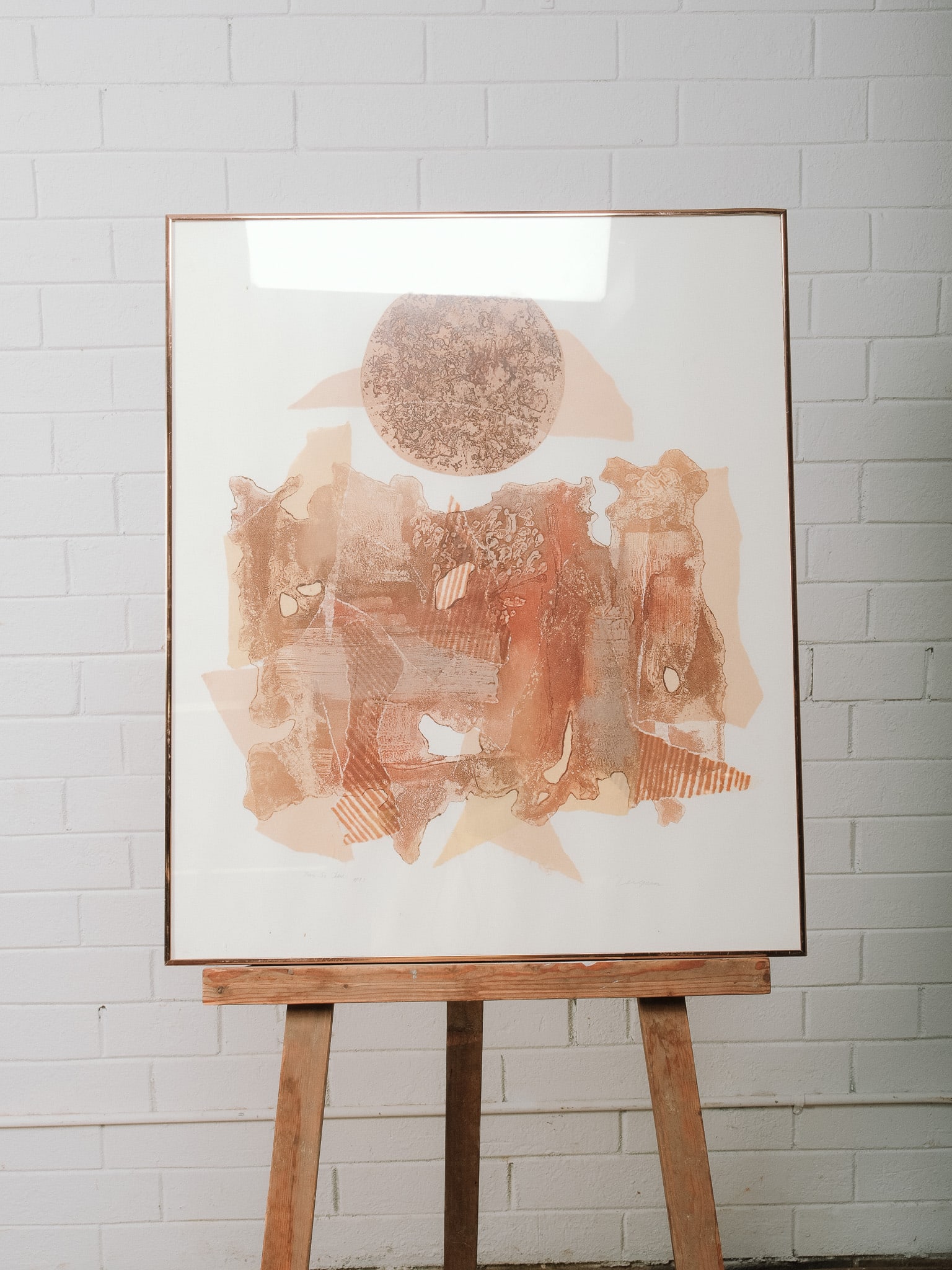 Abstract Earth Tone Mixed Media Original Art: Abstract mixed media art featuring layered geometric and organic forms in warm earth tones with circular motif above. Signed and numbered lower margin. Presented under glass in a thin metal