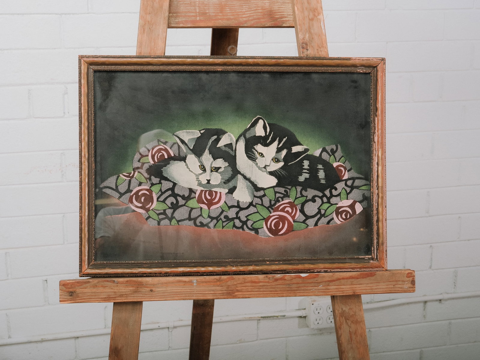 Framed Cat Artwork: Framed decorative artwork depicting two kittens resting among stylized roses against a rich green background. Kittens are painted/printed on fabric. With bold outlines and vibrant colors, this