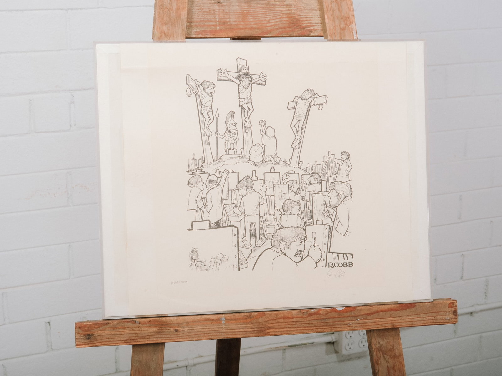 Signed R. Cobb Print: Signed print by R. Cobb depicting an art class sketching the Crucifixion, rendered in the artist's distinctive satirical style. Presented in a simple white frame, this thought-provoking work blends hu