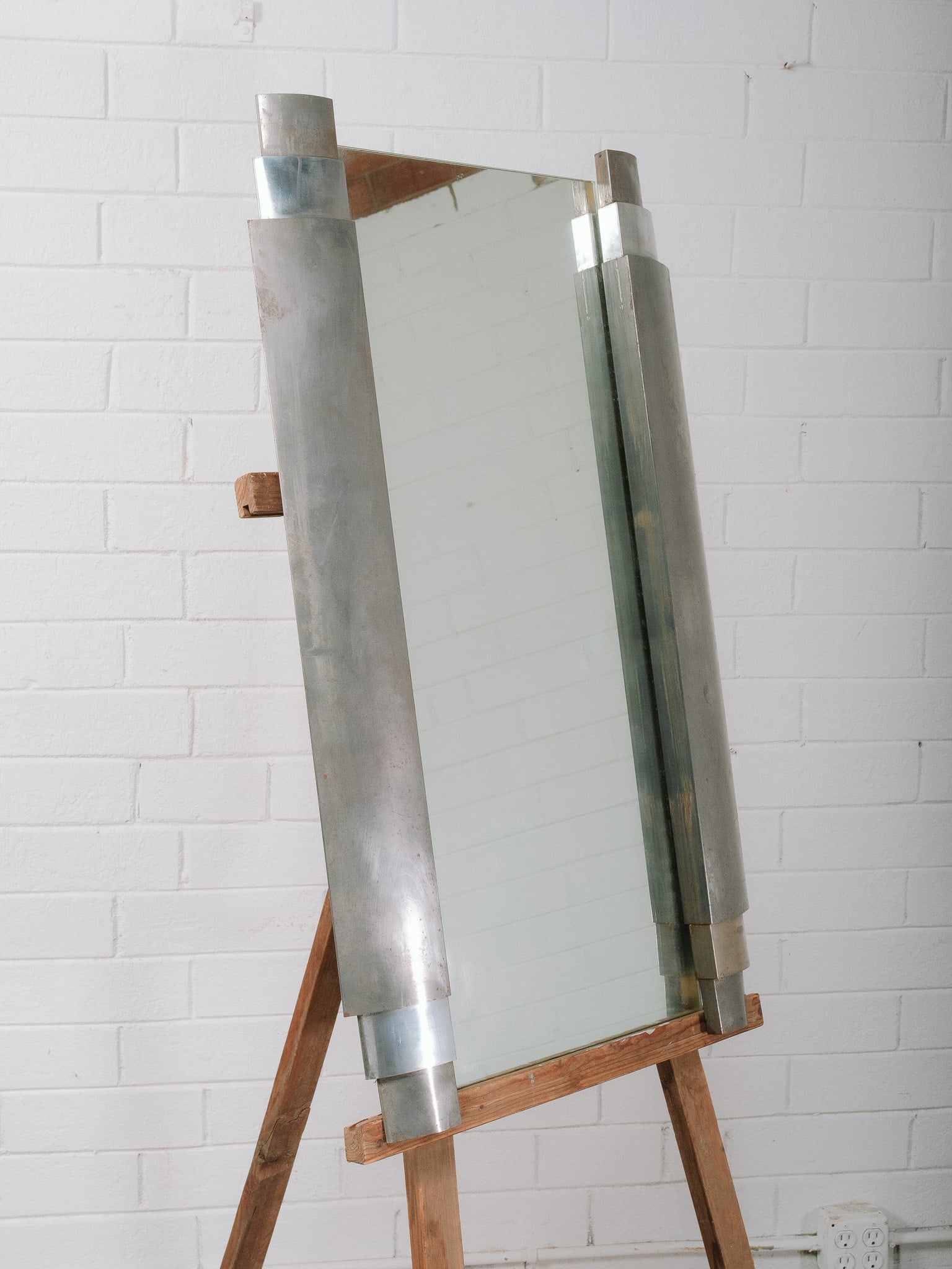 Art Deco Style Aluminum Mirror: Large Art Deco style wall mirror featuring a sculptural brushed aluminum frame with bold geometric styling. Its streamlined industrial aesthetic makes it an eye-catching statement piece for an