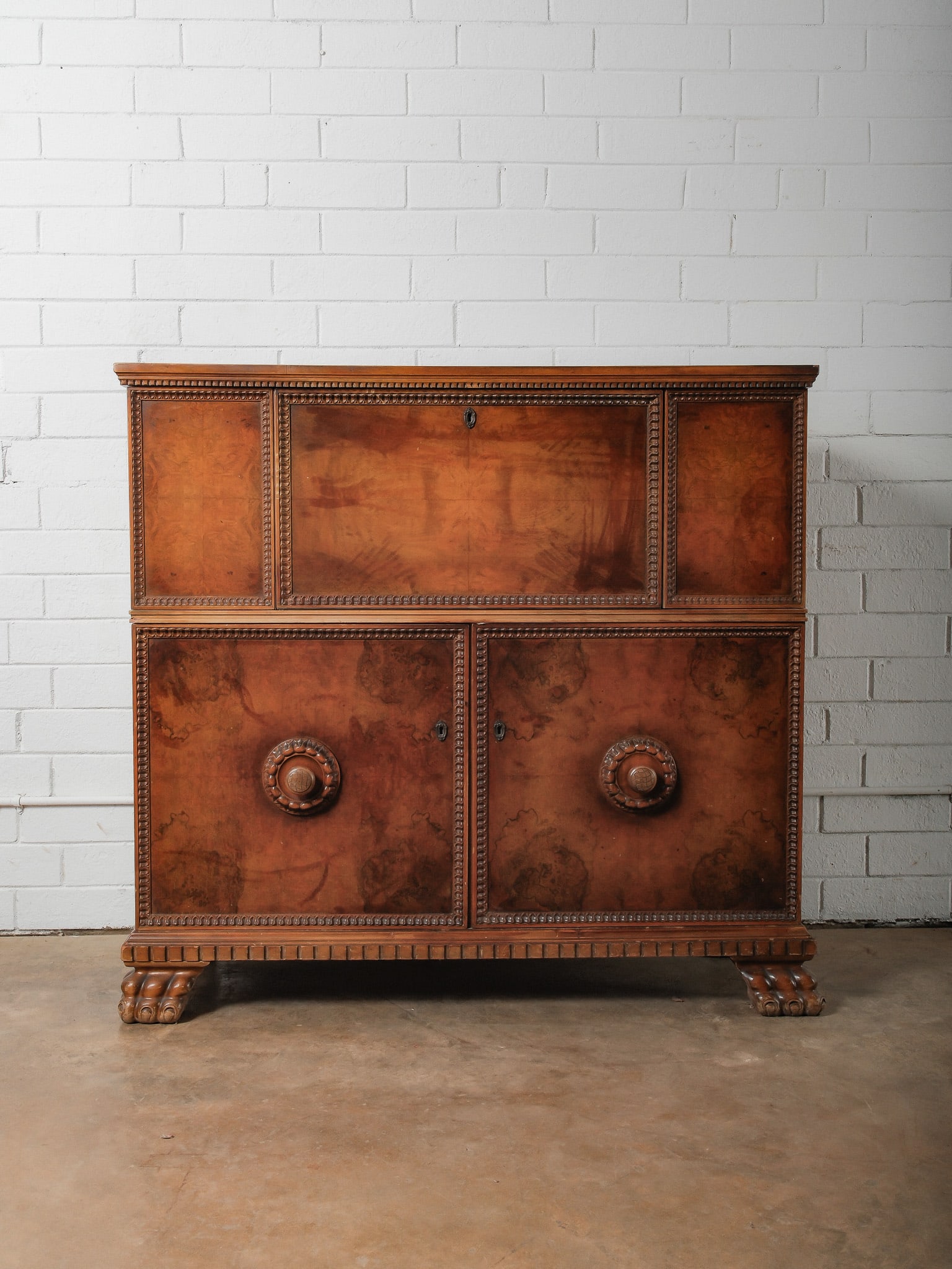 Burl Wood Folding Bar Cabinet: This striking campaign-style bar cabinet is crafted from richly figured burl wood, showcasing dramatic grain patterns and a warm, lustrous finish. The case features classic campaign design elements,
