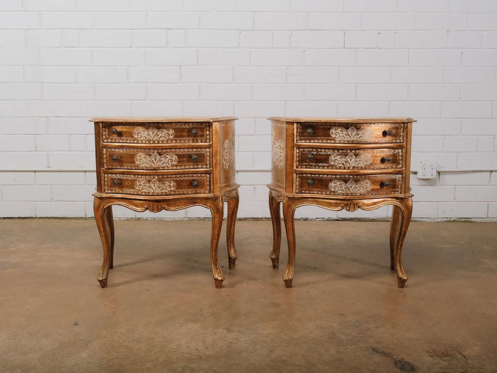 Pair of Venetian Style Nightstands: Pair of Venetian style nightstands featuring shaped tops above three drawers with decorative painted and gilt finishes accented by mirrored drawer fronts. Gracefully curved aprons and cabriole legs co