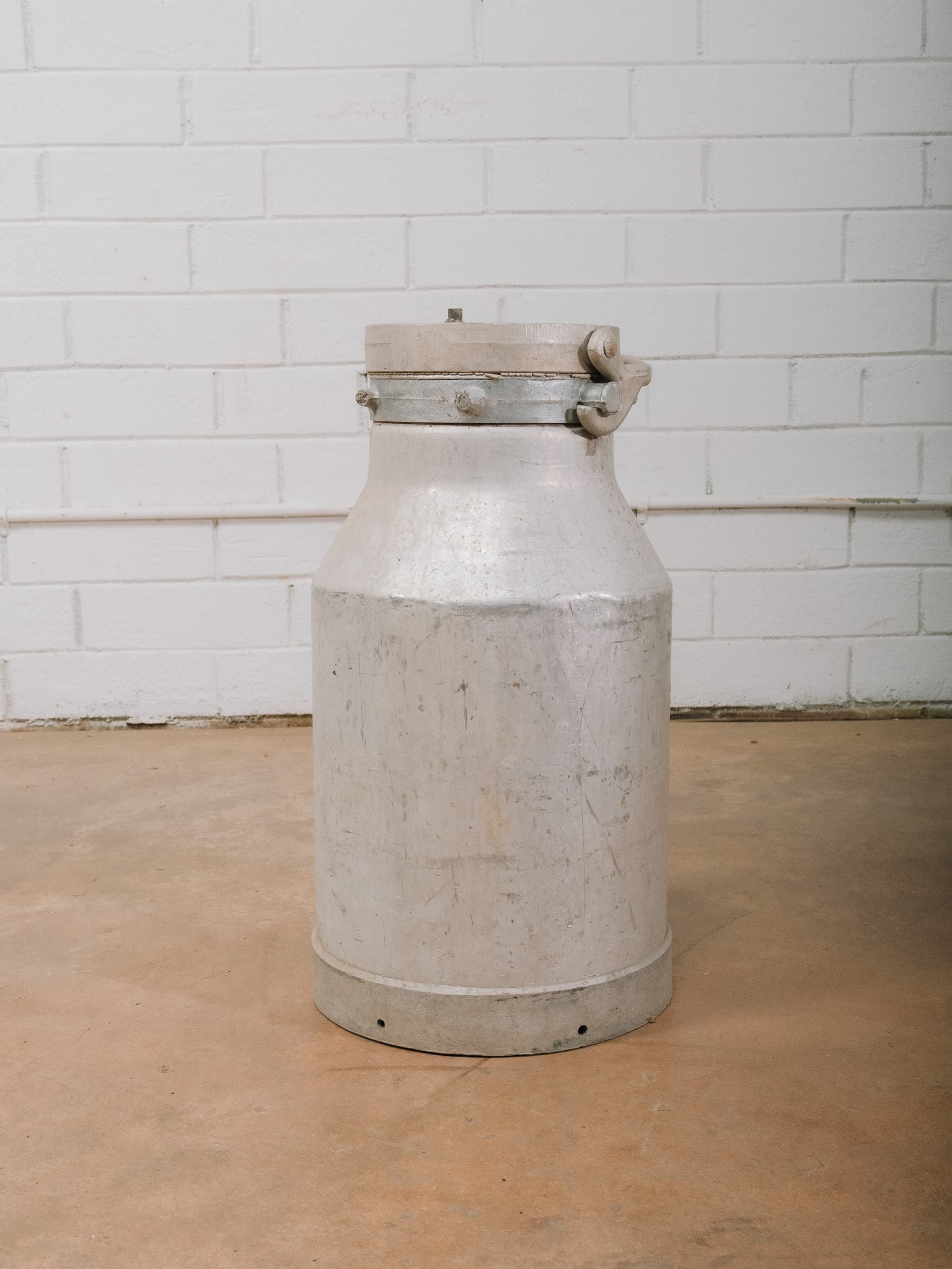 Vintage Aluminum Milk Can: Vintage aluminum milk can with locking lid and side latch hardware. A classic dairy collectible ideal for farmhouse or industrial décor.Approximate Dimensions: 22"h x 11"w x 11"d