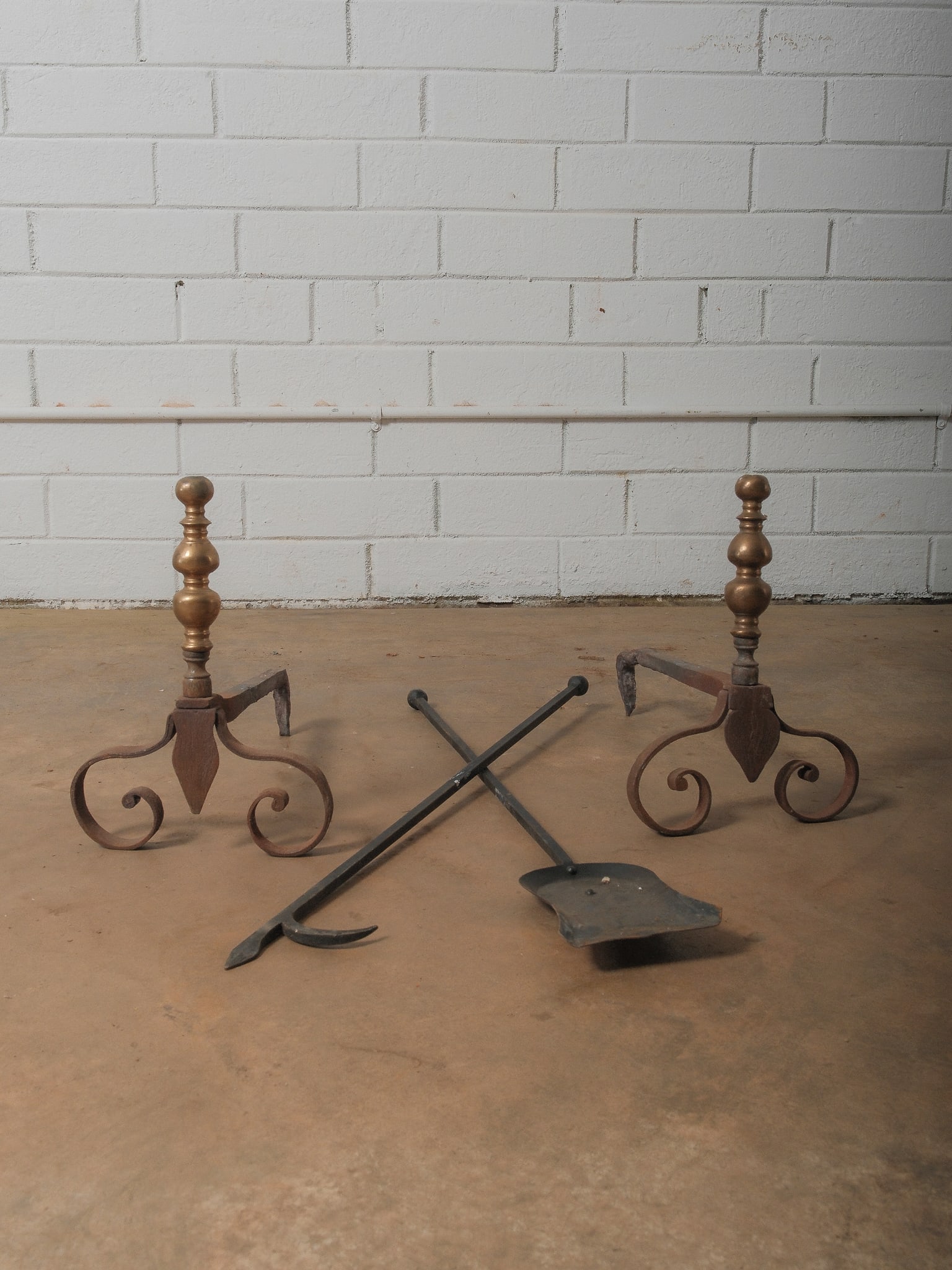 Antique Brass Andirons with Iron Tools: Pair of brass-topped andirons with ornate scrolling iron legs, accompanied by two iron fireplace tools. Beautifully aged with rustic patina, ideal decorative hearth set.