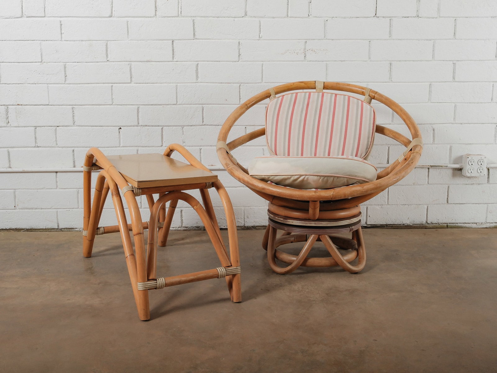 MCM Rattan Papasan Chair and Table: This mid-century chair features a sculptural rattan frame with a rounded design and woven detailing throughout. The chair is fitted with loose seat and back cushions upholstered in a striped fabric. A