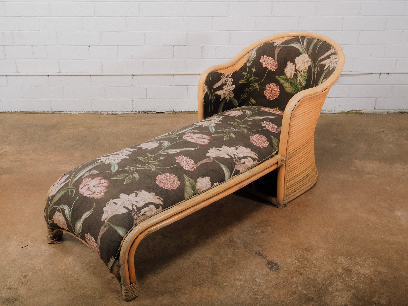 Vintage Bamboo Chaise Lounge: Vintage bamboo chaise lounge featuring a curved bamboo frame with wrapped corner details and a floral upholstered cushion. The graceful silhouette and natural bamboo construction make it an ideal
