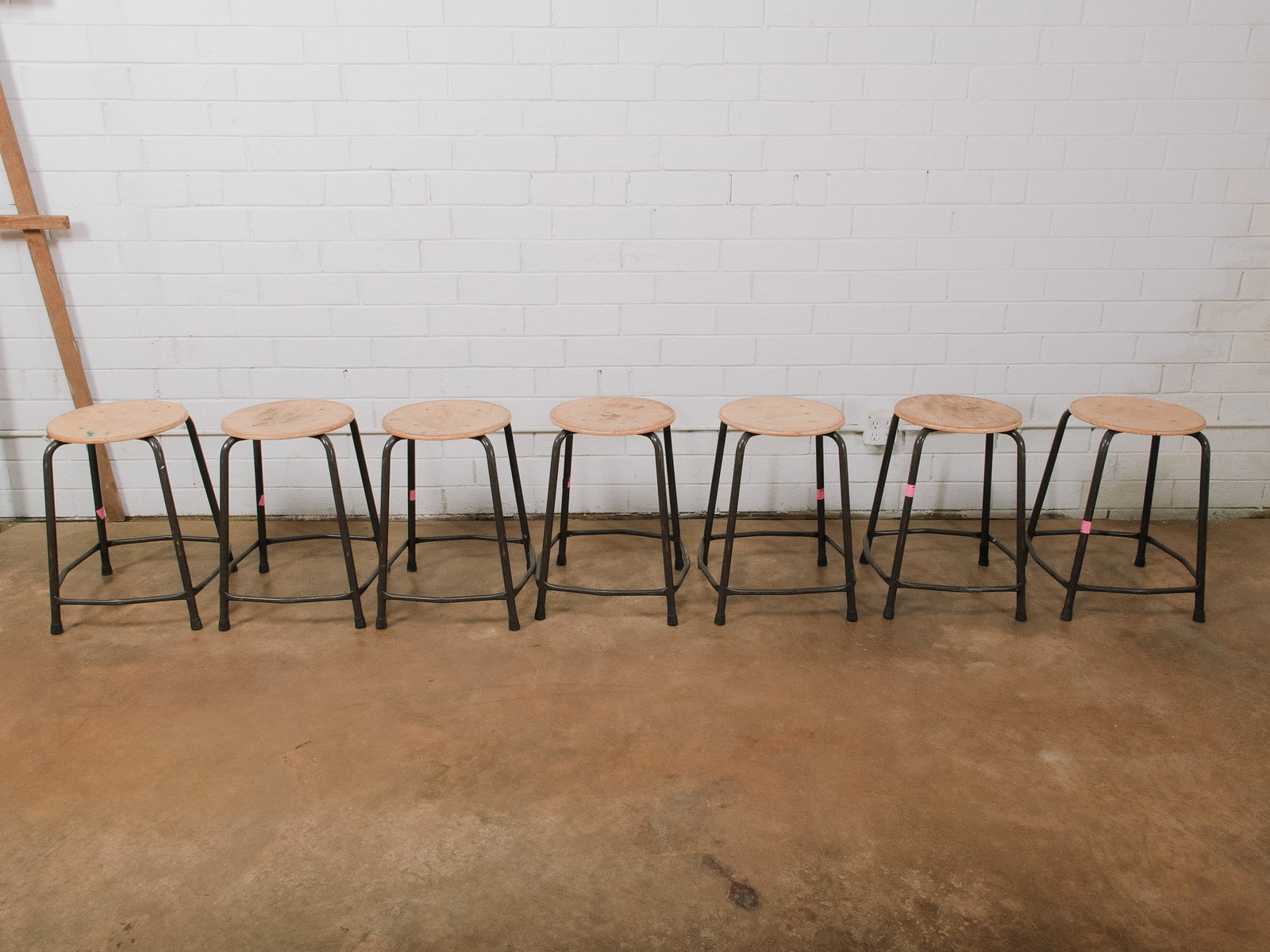 Set of 7 Industrial Stools: Set of seven industrial-style stools featuring round wood seats and black metal tubular bases with integrated footrests. Their durable construction makes them ideal for workshops, studios, kitchens, o