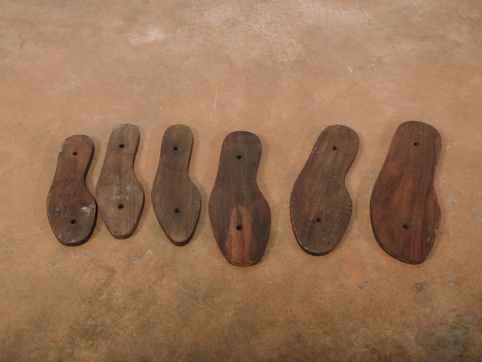 Collection of Wooden Shoe Last Soles: Group of six wooden shoe-sole lasts, each shaped and carved in varying sizes. Ideal for decorative displays or creative repurposing.Approximate Dimensions: 12"h x 5"w x 0.5"d