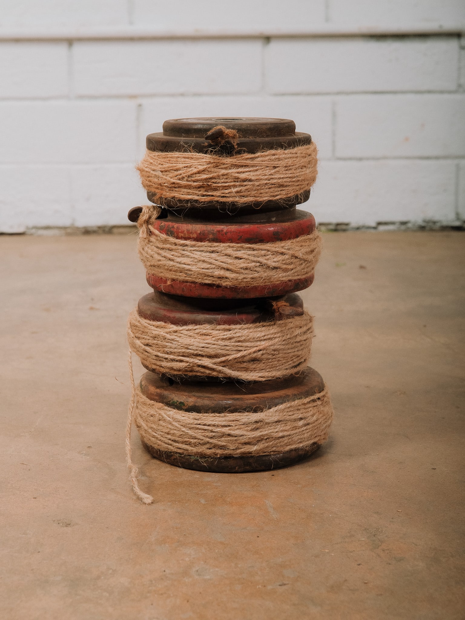 Lot of 4 Wooden Spools with Jute: Lot of four carved wooden thread spools wrapped with natural jute twine. Approximate Dimensions: 9"h x 5"w x 5"d