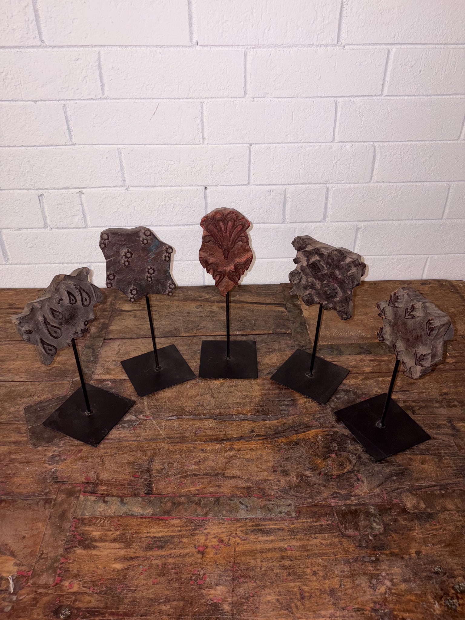 Lot of 5 Print Blocks on Stands: Collection of five hand-carved wooden textile printing blocks, each featuring a distinct traditional motif including florals, geometrics, and abstract forms. Displayed on custom metal stands, the grou