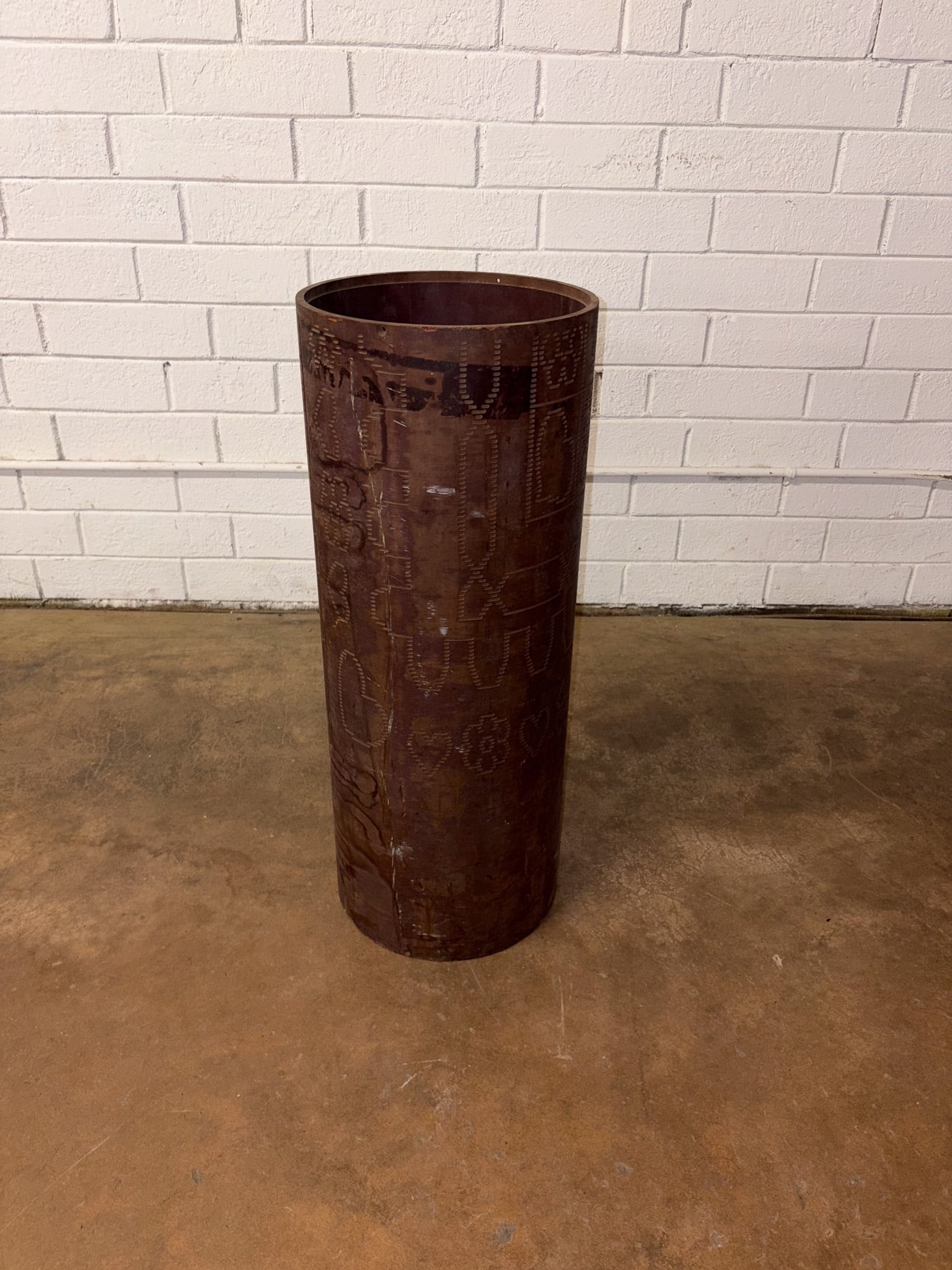 Large Punched Metal Vessel: Large cylindrical floor vessel crafted from hand-worked metal with an allover punched geometric and decorative pattern. The aged patina and rustic finish give the piece a strong architectural presence