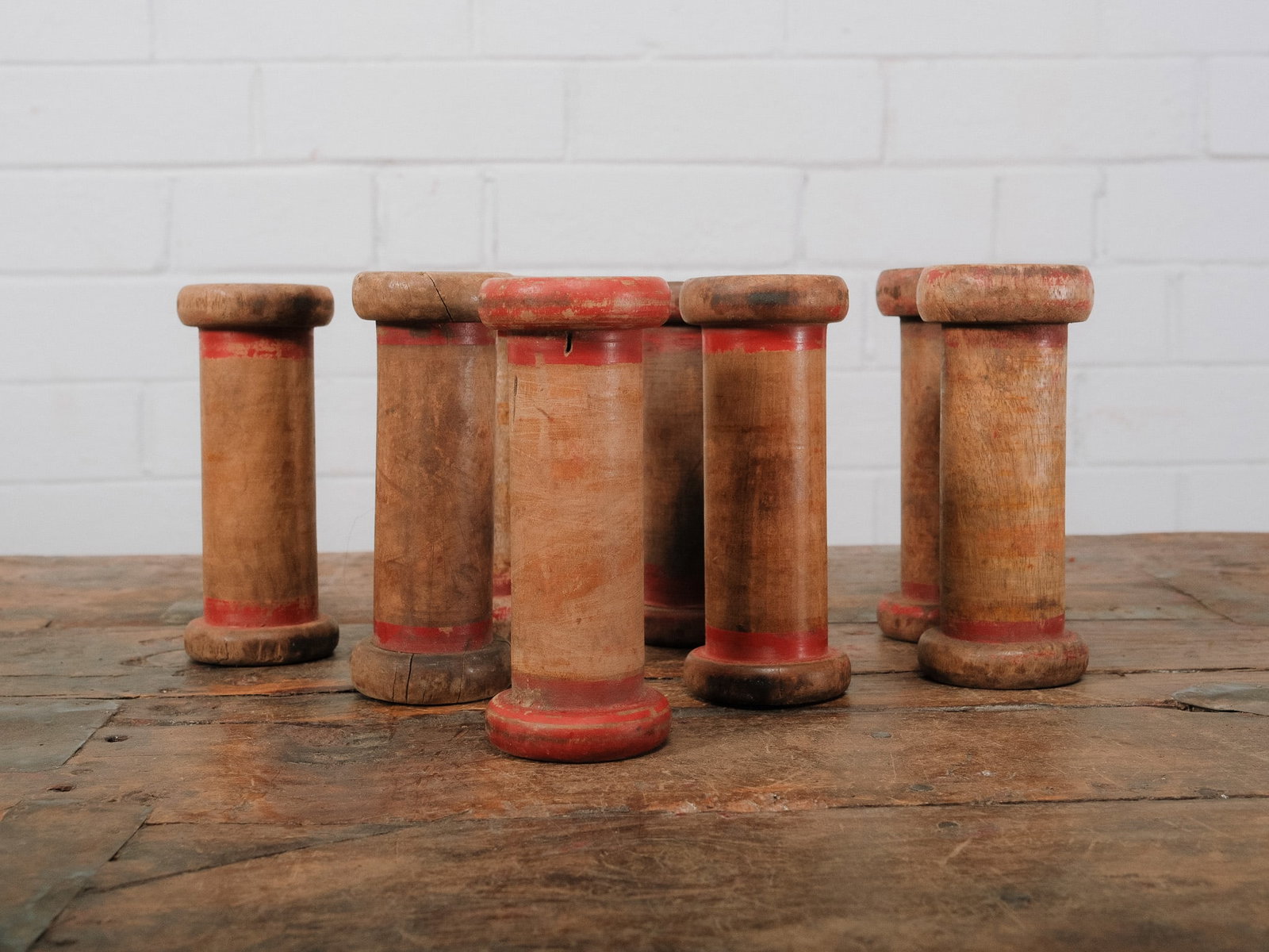 Group of 8 Wooden Textile Spools: Group of vintage wooden textile spools featuring turned hardwood construction with remnants of original red painted accents. These industrial spools display a well-worn patina and make excellent