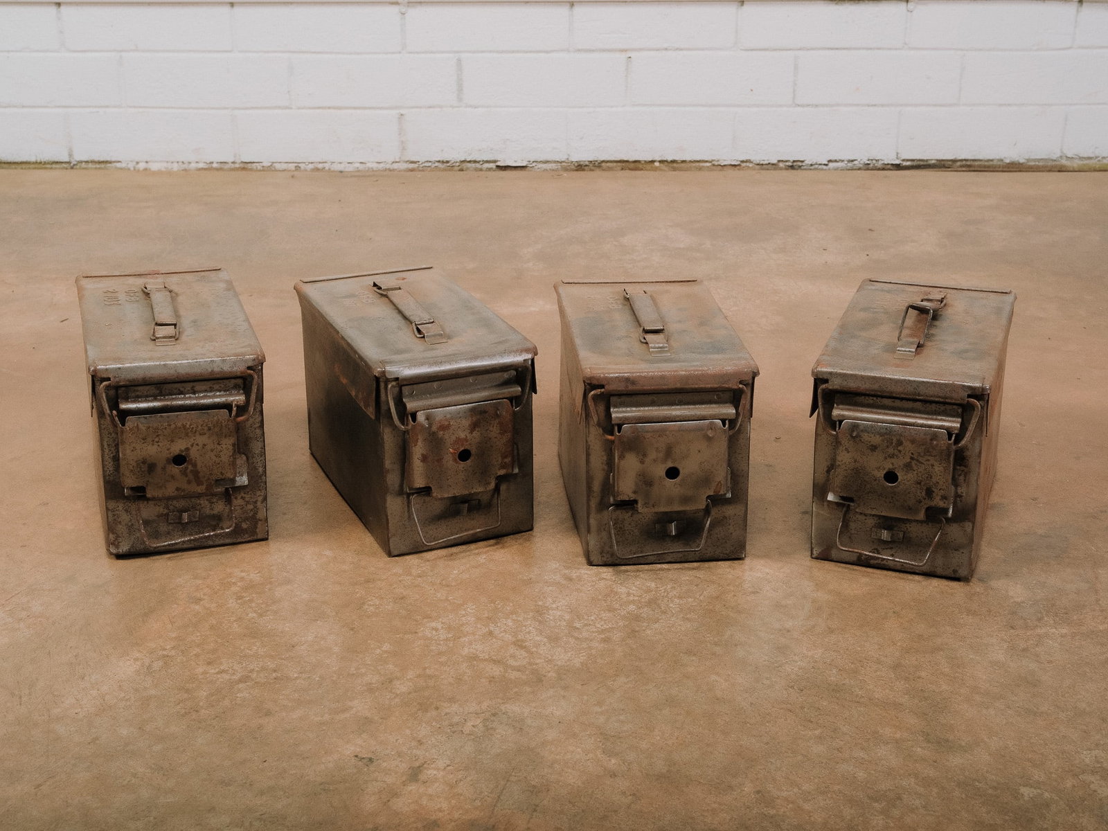 Vintage Metal Ammo Boxes: Collection of heavy-gauge steel ammunition boxes, each with original hinged lids, handles, and authentic field wear. Naturally aged patina with oxidation and surface marks throughout. Ideal for indust