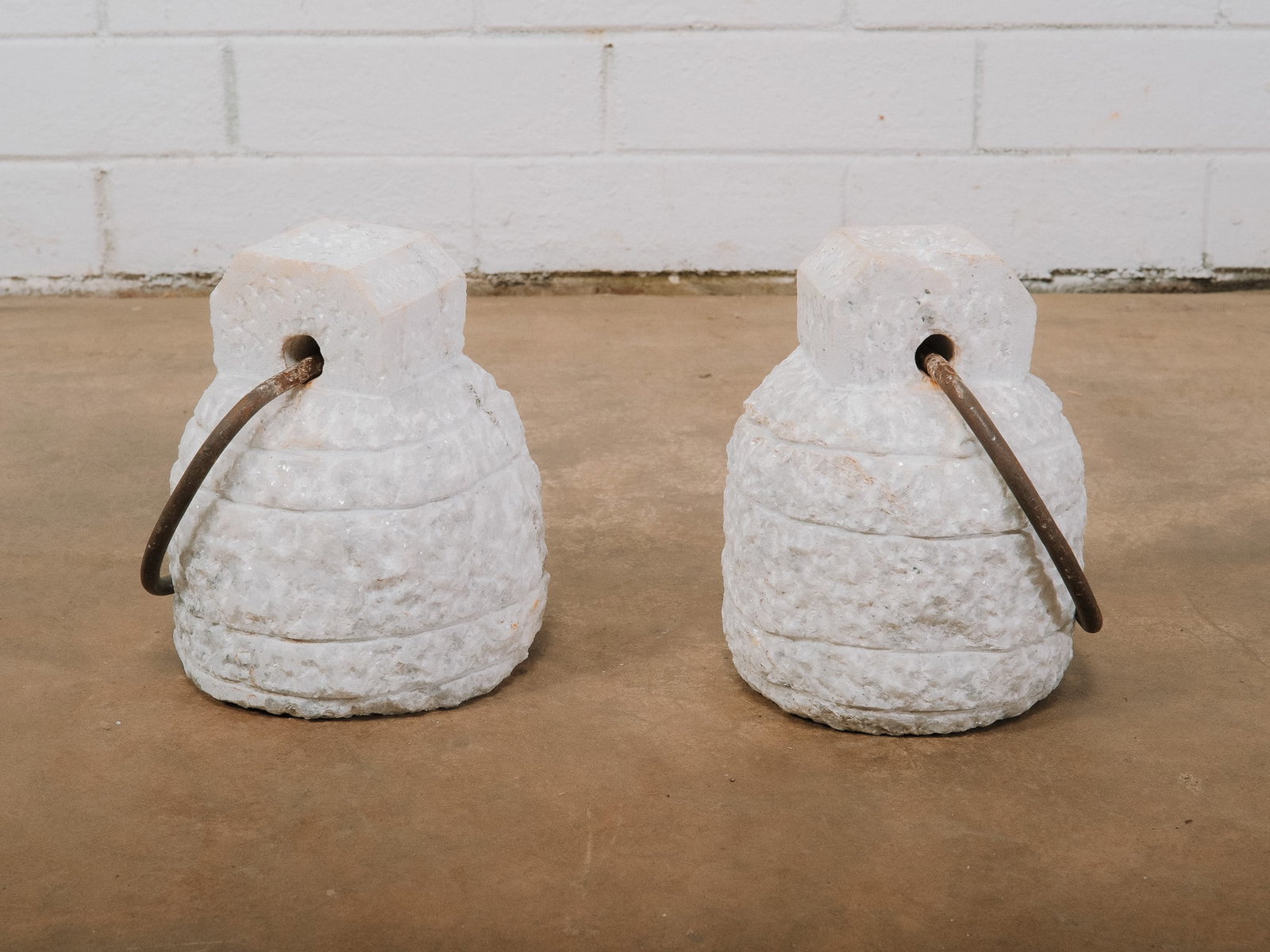 Pair of Hand Carved Stone Counterweights: Pair of carved stone counterweights. Inspired by traditional weights once used in India to measure grain, secure tents, or hold carpets in place. Rich in character, they features a rustic hand carved 