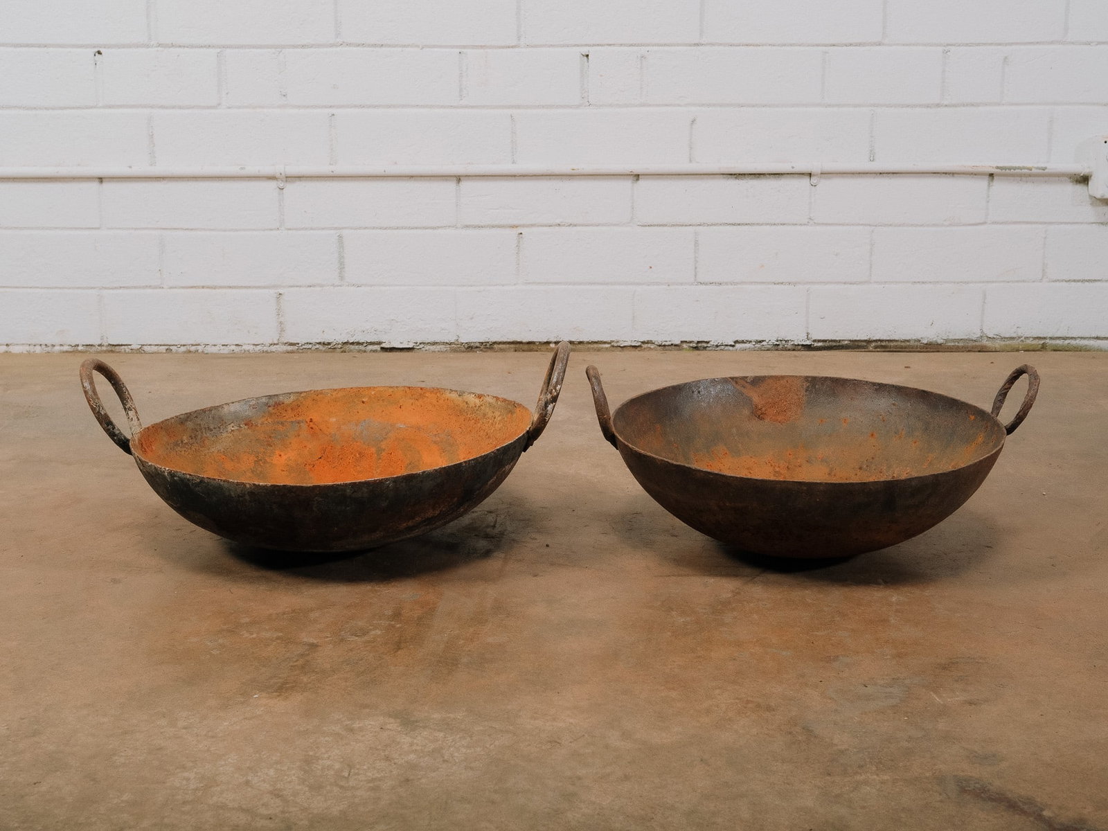 Pair of Vintage Iron Khaidis: Pair of antique hand-forged iron woks with loop handles. Rich surface patina and oxidation from age and use make them ideal decorative pieces for farmhouse, garden, or culinary