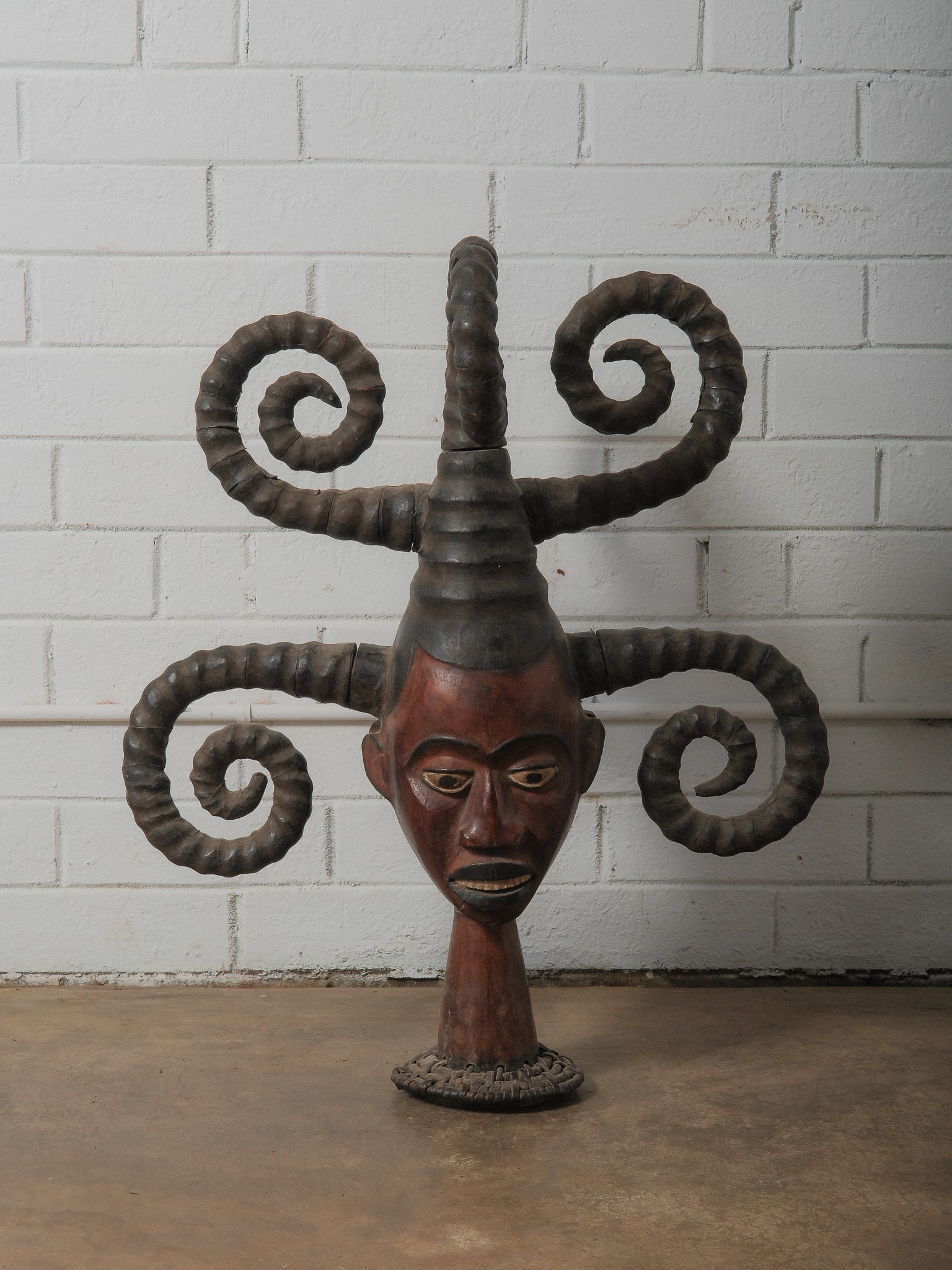 20th Century Ekoi Headdress: An extraordinary 20th-century Ekoi headdress crafted from wood. The face features wooden teeth set in an open mouth, along with painted eyes, brows, and keloids accentuating the temples. The