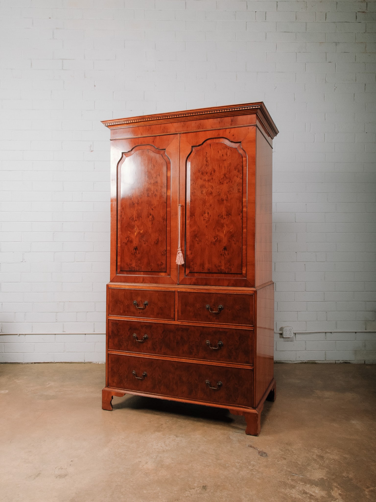 Burlwood Veneer Armoire: Burlwood veneer armoire featuring two paneled cabinet doors above five graduated drawers. The interior provides concealed storage, while the rich burl grain, molded cornice, and bracket feet lend