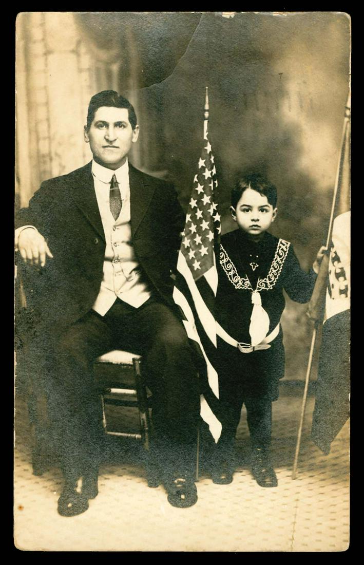 RPPC - Patriotic: Gripping image of father and son posed with flags. Bend, top center. Edge and corner wear.