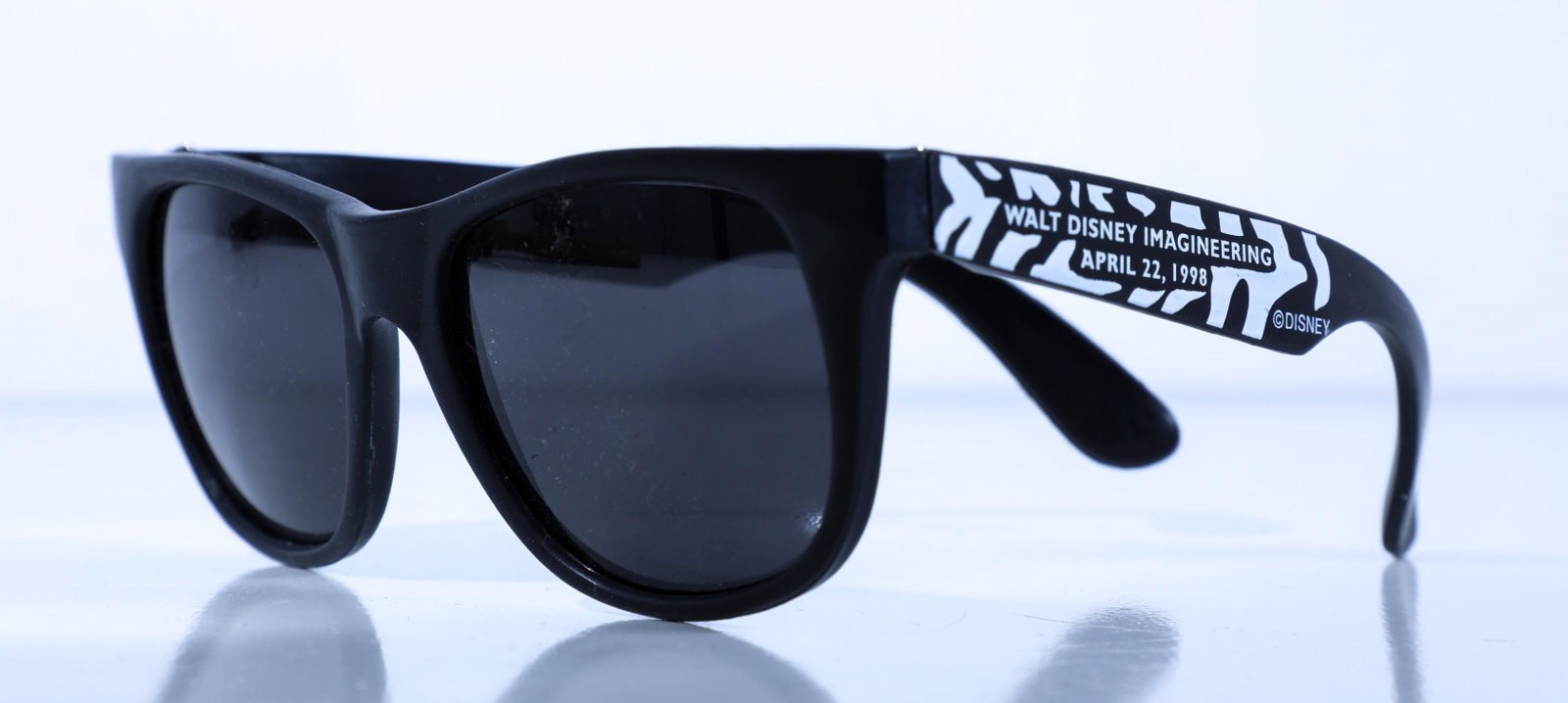 Disney Animal Kingdom WDI Cast Member Opening Day Zebra: (Disney Animal Kingdom, c. 1998). A rare pair of sunglasses given to Disney Imagineering cast members on the opening day of the park on April 22, 1998. The sunglasses are of a sleek black design with 