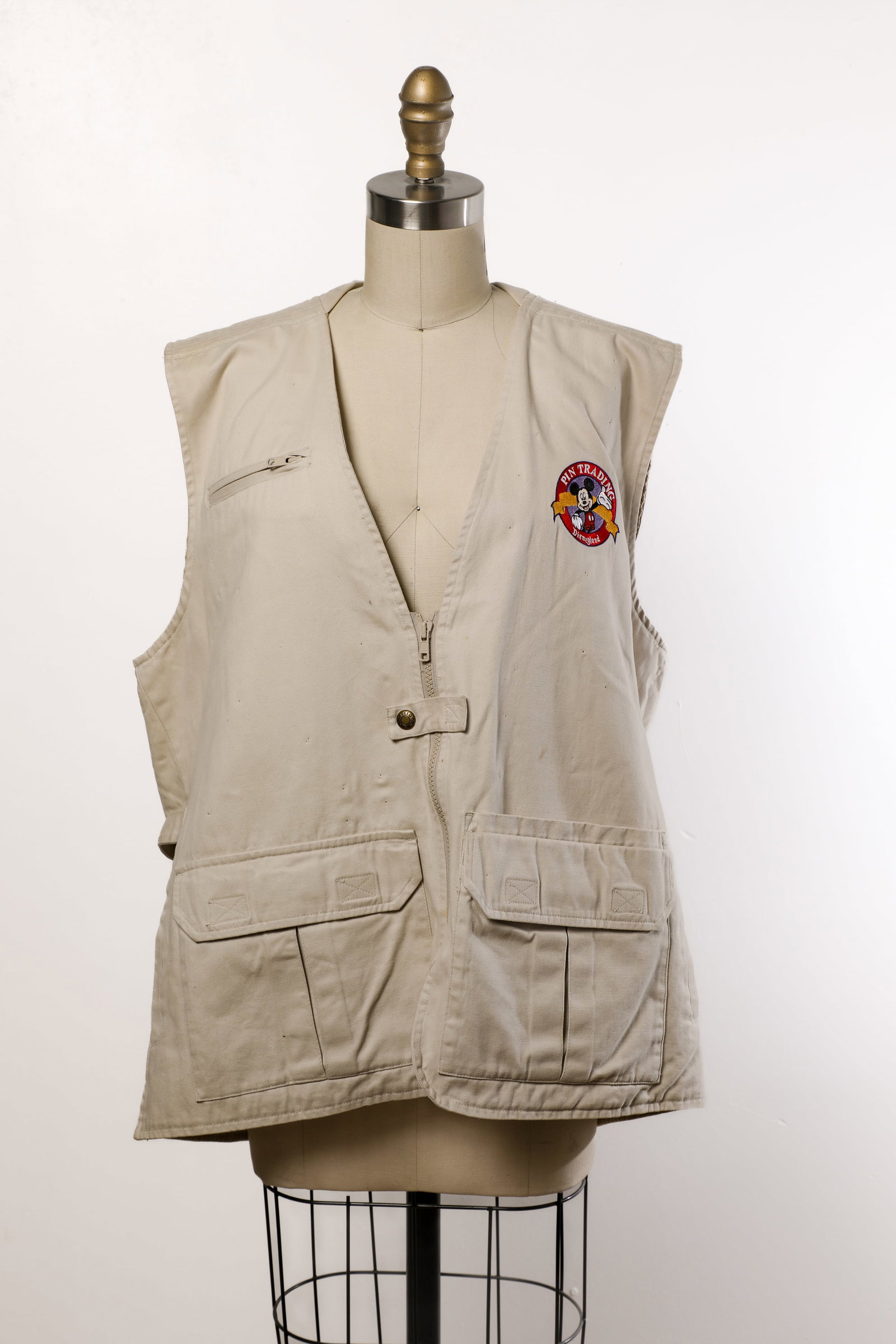 Disneyland Resort Cast Member Pin Trading Vest (2010s): “This is not a pin”… Show your pride for pins with this official Disneyland Resort Pin Trading Utility Vest! The khaki-beige garment features zippered chest pocket, two large front flap pock