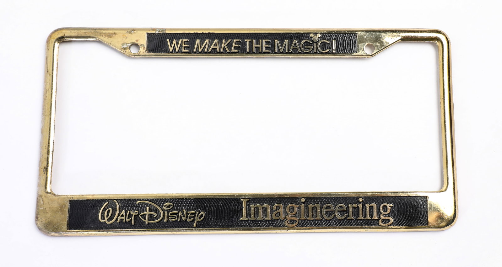 Walt Disney Imagineering Exclusive License Plate Frame (1990s).: “We make the magic happen!” This gold-toned edition of the novelty license plate frame was an exclusive, available for purchase by Walt Disney Imagineers! Occasionally, Imagineers have designe
