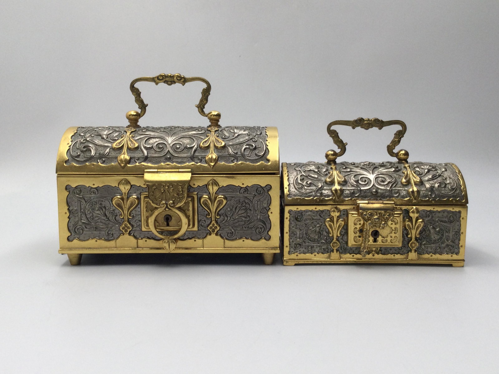 Pair of German Brass Treasure Chest Jewelry Boxes: Pair of German Brass Treasure Chest, one a musical box, both velvet lined. Music box is approximately 6.25 inches wide x 4 inches tall, trinket box is approximately 5.25 inches wide x 2.75 inches tall